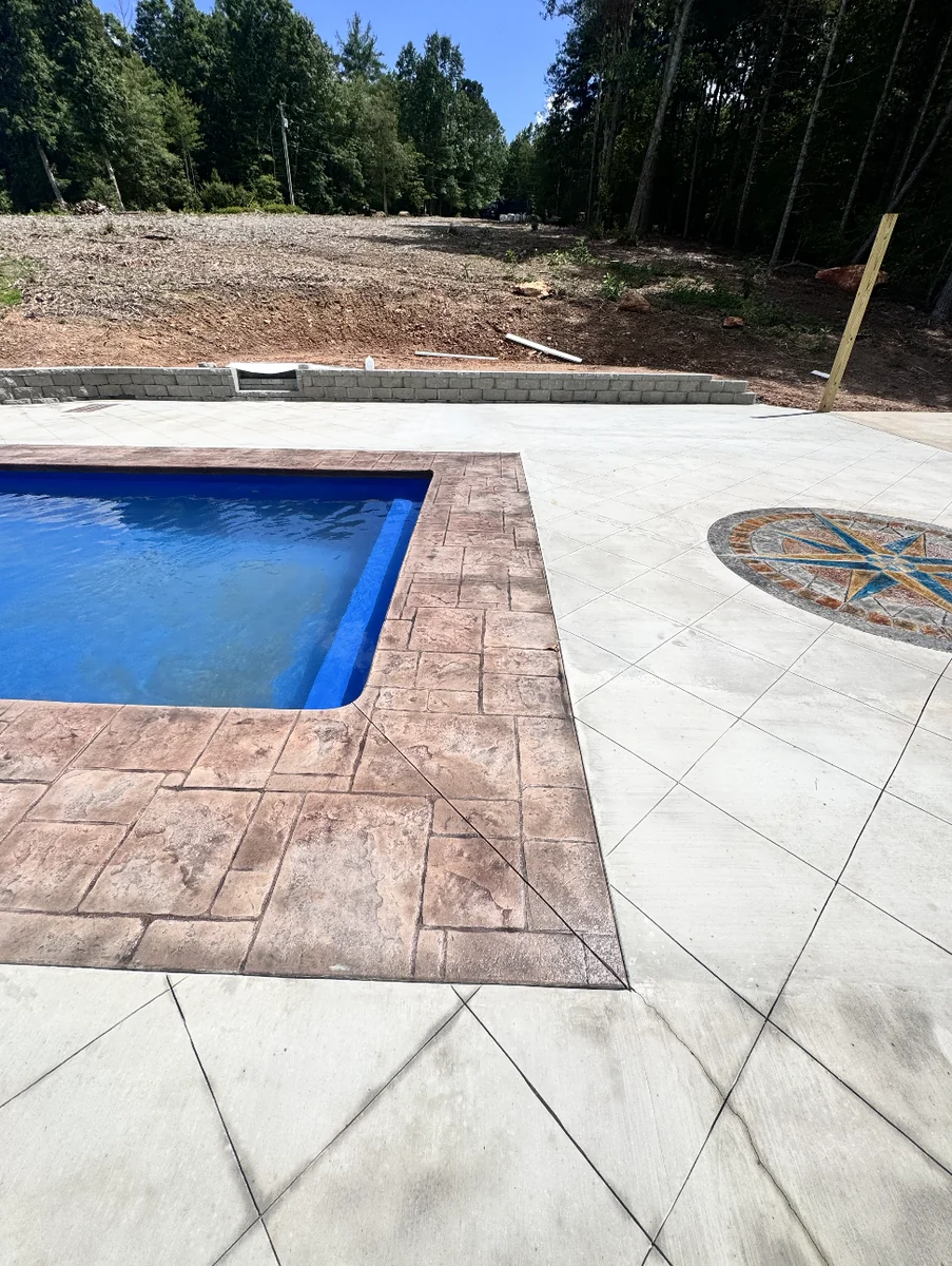 Close view of stamped ashlar-pattern pool coping in warm rust tones meeting a diamond-scored concrete deck &mdash; The Foothills Concrete Company
